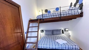 A bunk bed with a ladder, a bedside table with a lamp, and a checkered bedspread.