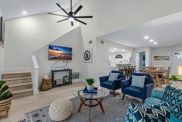 A modern living room with a staircase, a dining area, and a kitchen.