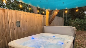 A hot tub with a wooden fence and string lights in a backyard setting. - Hot Tub~Vilano Beach Serene Walk~parking~2 ACs (St. Augustine)