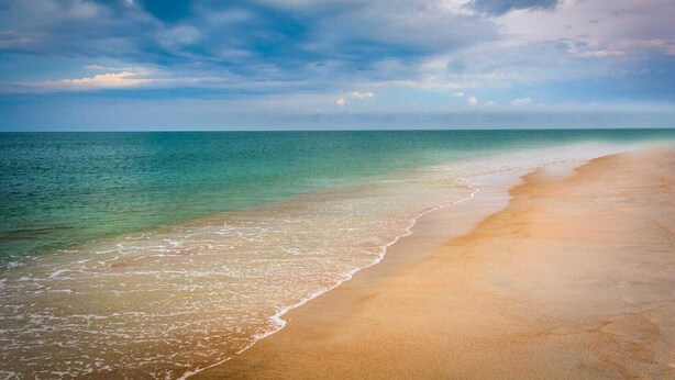 A beach with clear water and a sandy shore under a cloudy sky. - Hot Tub~Vilano Beach Serene Walk~parking~2 ACs (St. Augustine)