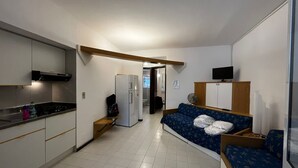 A compact hotel room with a kitchenette, a sofa bed, a television, and a small desk. - Apartment in beautiful resort on the Gargano (Vieste)