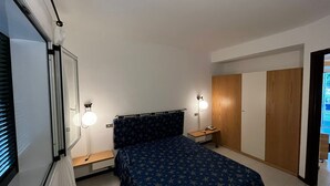 A bedroom with a bed, bedside tables, a nightstand, a lamp, and a wardrobe. - Apartment in beautiful resort on the Gargano (Vieste)