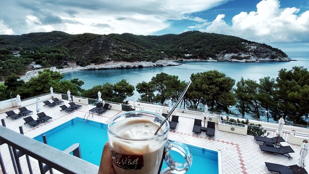 A poolside view with a glass of coffee, lounge chairs, and a scenic view of a coastline. - Apartment in beautiful resort on the Gargano (Vieste)