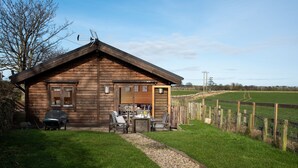 Eine Holzhütte mit Veranda, Grill und Tisch mit Stühlen.