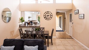 Une cuisine moderne avec des meubles blancs, une table à manger et un ventilateur de plafond.