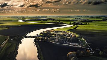 Une vue aérienne d’une rivière serpentant à travers un paysage rural, avec des champs et un petit village.