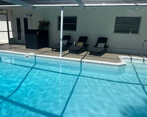 Une piscine avec des chaises longues et un espace abrité.