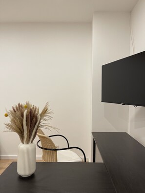 Relax in a serene space with a flat-screen TV, wicker chair, and elegant vase.