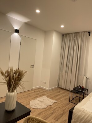 Relax in this serene bedroom with a large window, plush bed, and elegant decor.