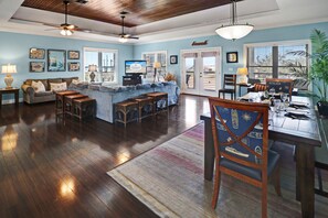 A spacious living room with a large sofa, wooden coffee table, and a dining area with a table and chairs.
