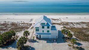 A modern beach house with a sloped roof, large windows, and a concrete driveway. - Ginger Snap: 5 BR Beachfront Home- Elevated Pool, Pet Friendly, Sleeps 20! (St. Joe Beach)