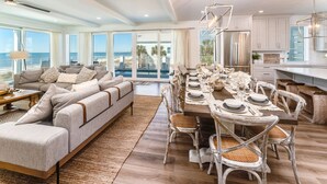 A spacious living room with a large sofa and a dining area with a long table set for six.