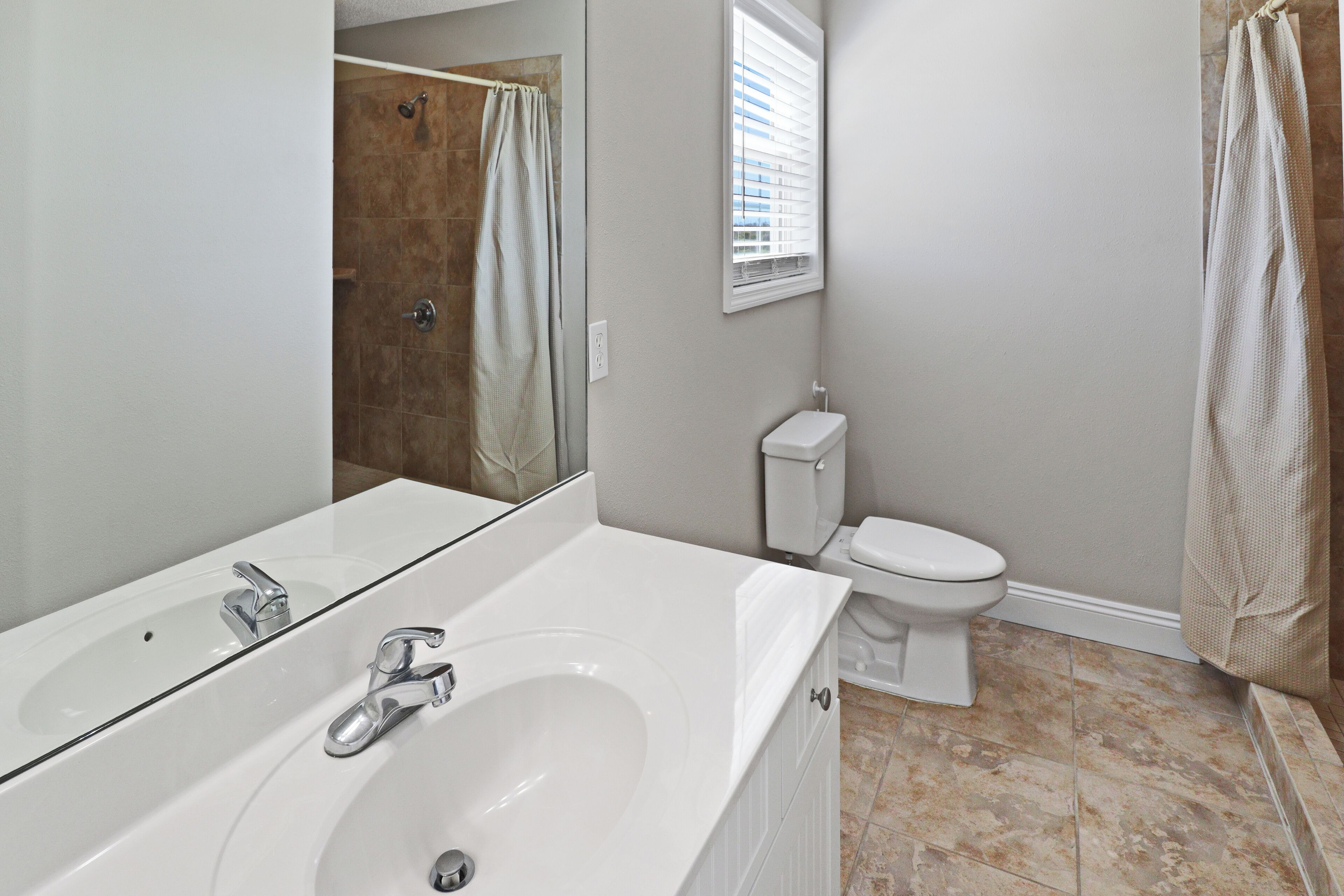 Une salle de bain avec un lavabo blanc, un miroir et des toilettes.