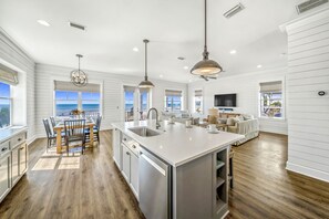 A spacious kitchen with a large island, white cabinetry, and a view of the ocean.
