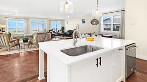 A modern kitchen with a large island, white cabinetry, and a built-in dishwasher. - Living the Dream MB: 4th of July week available as a Friday or Saturday check in (Mexico Beach)