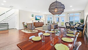 A spacious dining area with a wooden table set for six, surrounded by white chairs. - Living the Dream MB: 4th of July week available as a Friday or Saturday check in (Mexico Beach)