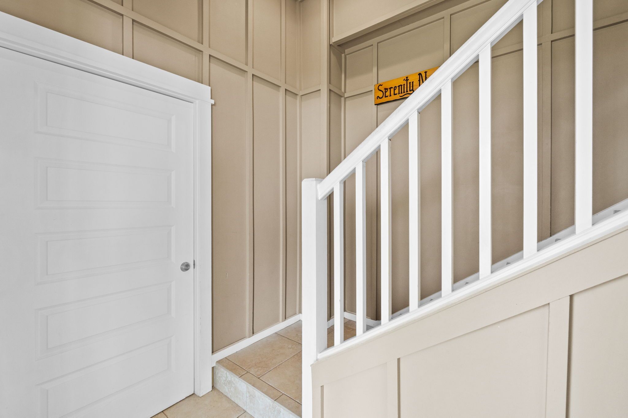 A staircase with a white railing and beige walls.