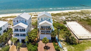 A coastal property with two large houses, a paved driveway, and a beach in the background. - Memory Maker: Beachfront, Fire Pit, Sleeps 18! (St. Joe Beach)