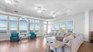A spacious living room with a large grey sofa, teal armchairs, and a wooden coffee table. - Memory Maker: Beachfront, Fire Pit, Sleeps 18! (St. Joe Beach)
