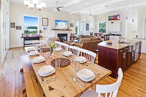 A spacious living room with a fireplace, a dining area set for a meal, and a kitchen with modern appliances.