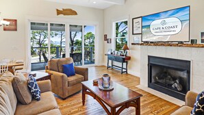 Amplia sala de estar con chimenea, televisor grande y vistas al exterior.