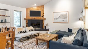 A modern living room with a fireplace, a sofa set, a coffee table, and a TV mounted on the wall. - Outpost: Balsam Lodge B7 (Wilson)