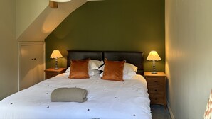 Une chambre à coucher avec un lit, deux tables de chevet, un luminaire suspendu et une porte.