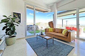Un salon moderne doté d’une grande porte-fenêtre coulissante donnant sur une terrasse extérieure.