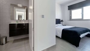 Ein modernes Schlafzimmer mit Bett, Nachttisch und Fenster.