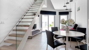 Ein modernes Interieur mit Treppe, Essbereich und runder Esstisch sowie einer Sitzecke.