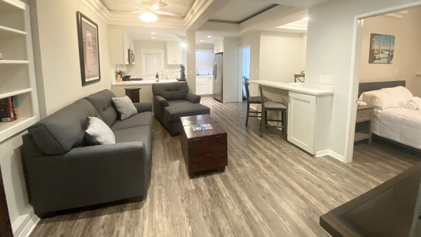 Een moderne woonkamer met een grijze bank, een salontafel en een eethoek met een witte tafel en stoelen.