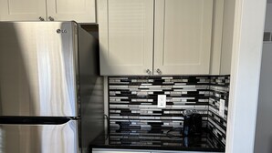 A kitchen with white cabinets, a stainless steel refrigerator, and a black and white tiled backsplash. - Newly Renovated 2 Bed 2 Bath Home (Lincoln)