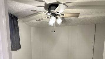 Une pièce dotée d’un ventilateur de plafond, d’un sol recouvert de moquette et de deux panneaux blancs fixés au mur.