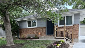 A residential house with a brick facade, a black front door, and a wooden front porch. - Newly Renovated 2 Bed 2 Bath Home (Lincoln)