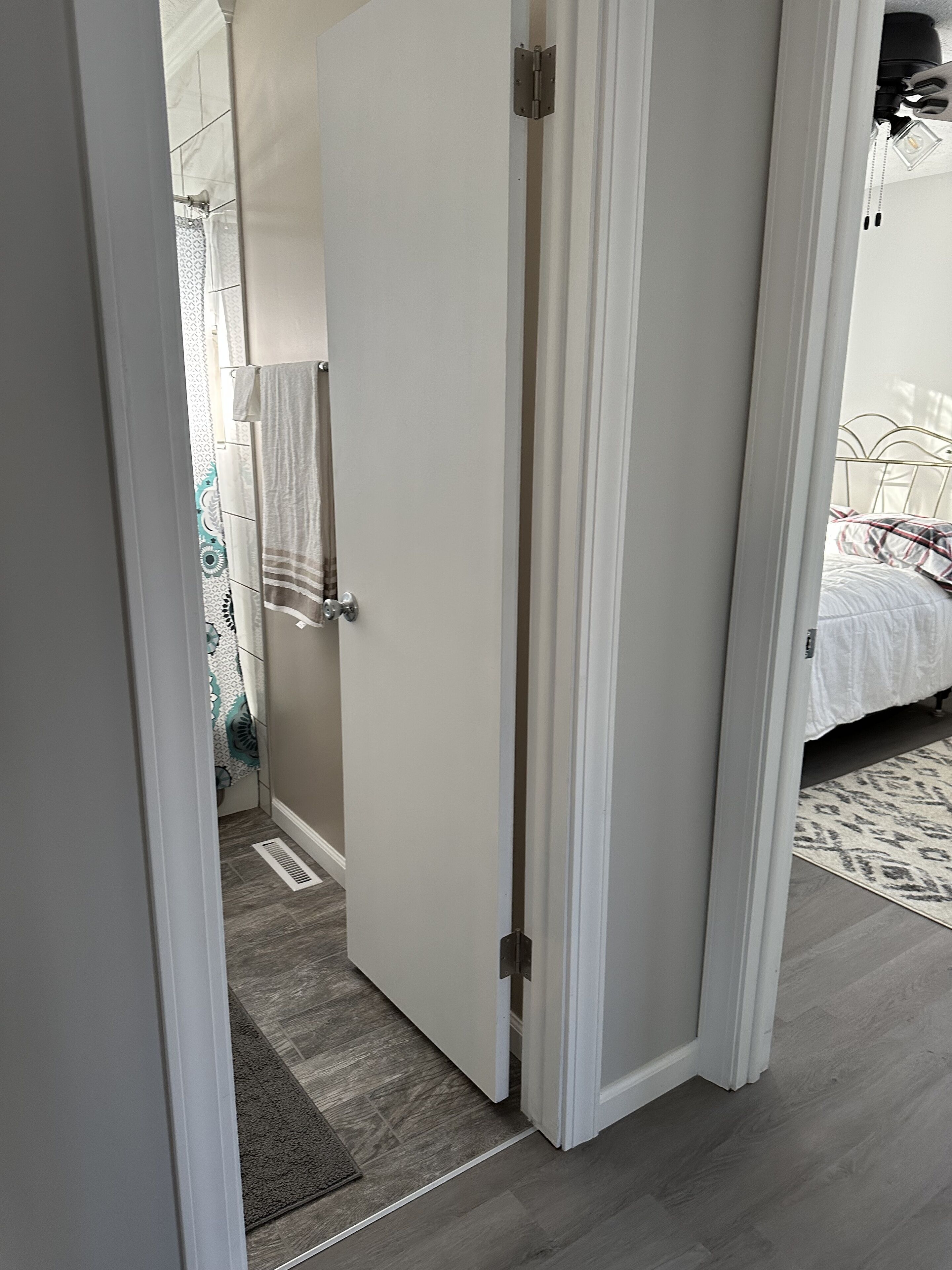 A narrow hallway with a door leading to a bathroom and a bedroom.
