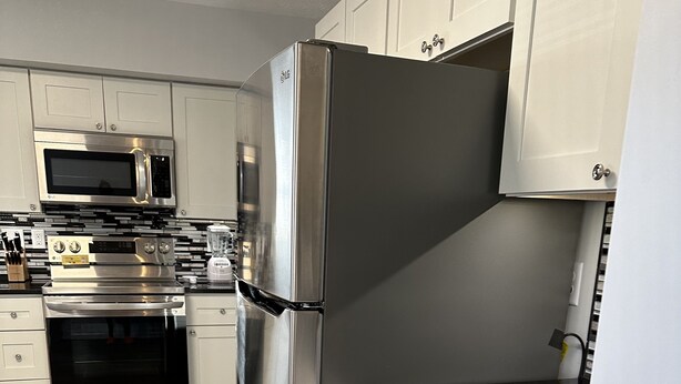 A modern kitchen with stainless steel appliances, white cabinetry, and a wooden floor. - Newly Renovated 2 Bed 2 Bath Home (Lincoln)