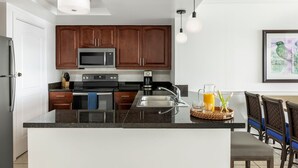 Une cuisine moderne avec des meubles en bois foncé, des appareils électroménagers en acier inoxydable et un plan de travail en granit.