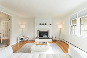 A modern living room with a fireplace, white sofas, and a wooden coffee table.