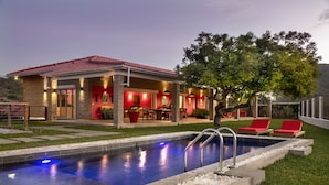 Ein Haus mit Swimmingpool, roter Gartenmöbeln und einer Terrasse.