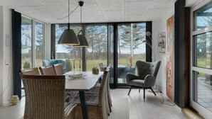A modern dining area with wicker furniture, a table, and pendant lighting. - 3 bedroom cozy home in Thyholm (Thyholm)