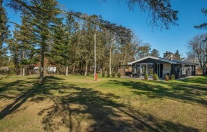 Une maison moderne dotée d’une grande terrasse, entourée d’arbres et offrant une vue sur un ciel dégagé.