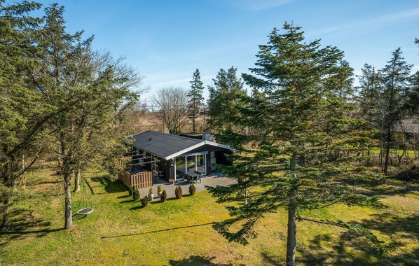 Une maison moderne dotée d’une terrasse, entourée d’arbres.