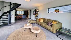 A modern living room with a staircase, a sofa, a coffee table, and a bookshelf. - Lovely home in Balk with kitchen (Balk)
