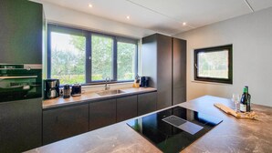 A modern kitchen with a built-in stove, a sink, and a window with blinds. - Lovely home in Balk with kitchen (Balk)