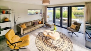 A modern living room with a sofa, two armchairs, a coffee table, and a bookshelf. - Lovely home in Balk with kitchen (Balk)