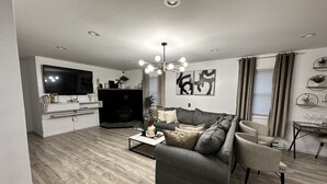 Ett modernt vardagsrum med en grå soffa, ett soffbord och en tv som är monterad på väggen.