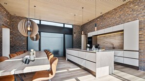 A modern kitchen with a large island, wooden flooring, and a brick wall. - Gorgeous home in Ebeltoft with kitchen (Ebeltoft)