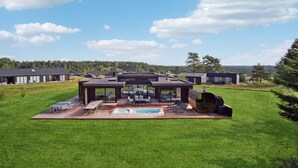 A modern outdoor living area with a pool, seating, and a barbecue grill. - Gorgeous home in Ebeltoft with kitchen (Ebeltoft)