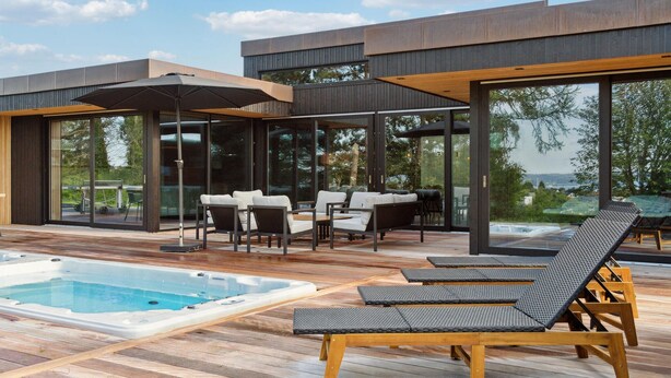 A modern outdoor deck with a hot tub, lounge chairs, and a dining area with a table and chairs. - Gorgeous home in Ebeltoft with kitchen (Ebeltoft)