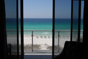 A view from a window overlooking a beach with umbrellas and a fence. - STUNNING BEACHFRONT CONDO WITH GREAT BALCONY VIEW IN THE HEART OF DESTIN  (Destin)